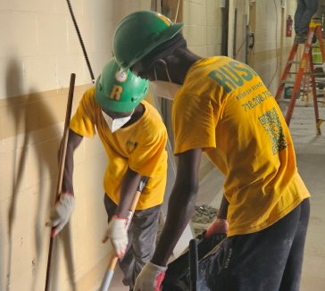 Two Rush laborers sweeping a floor during construction